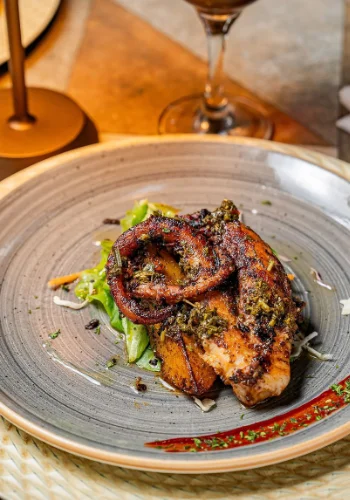 Plato de pescado a la plancha con guarnición de verduras y copa de vino tinto como acompañamiento